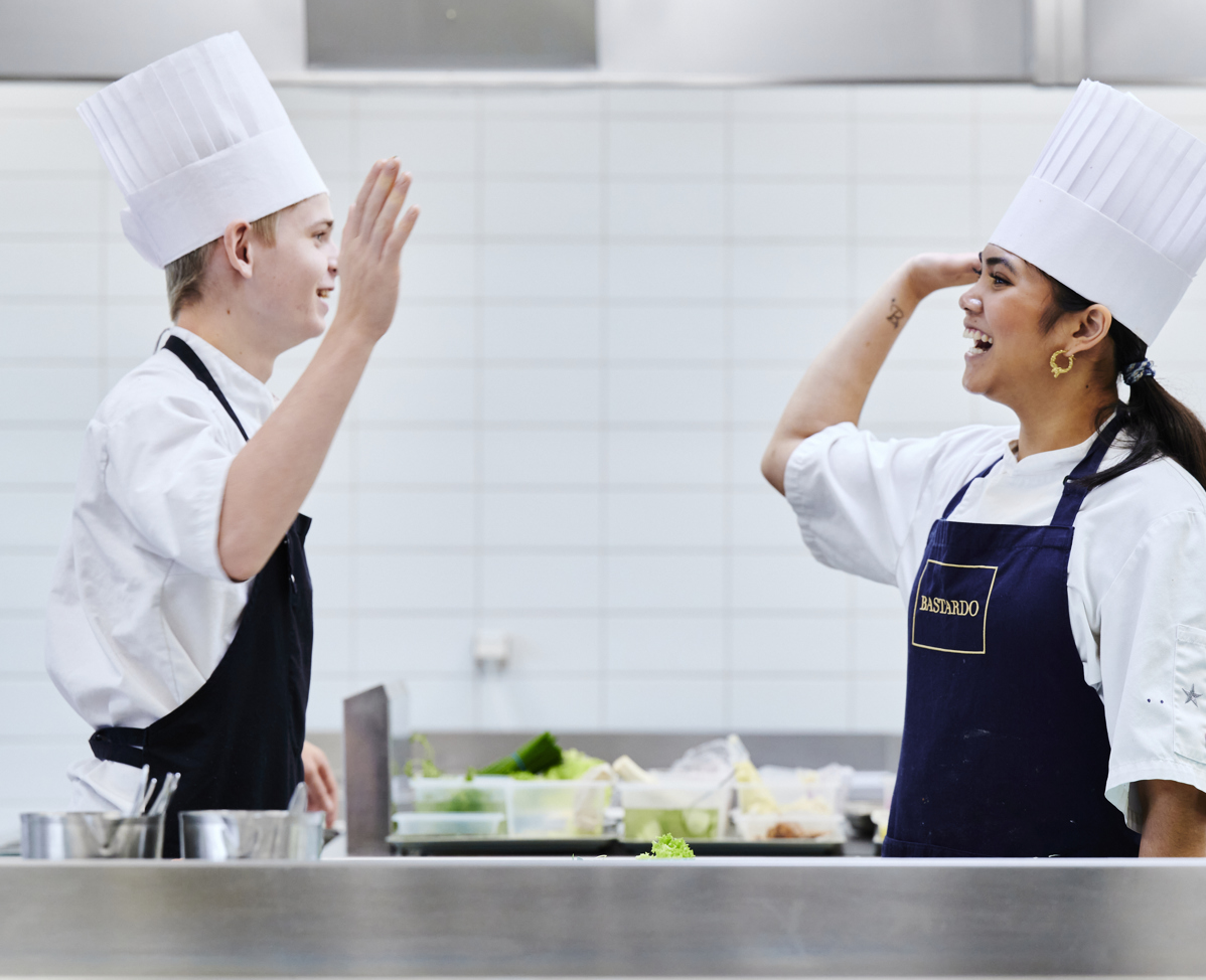 Dreng og pige i køkkenet giver high-five til hinanden