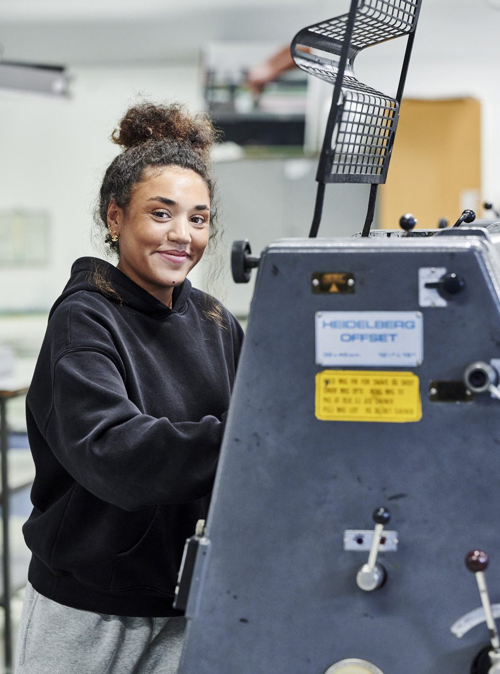 Pige ved offset-maskine smiler