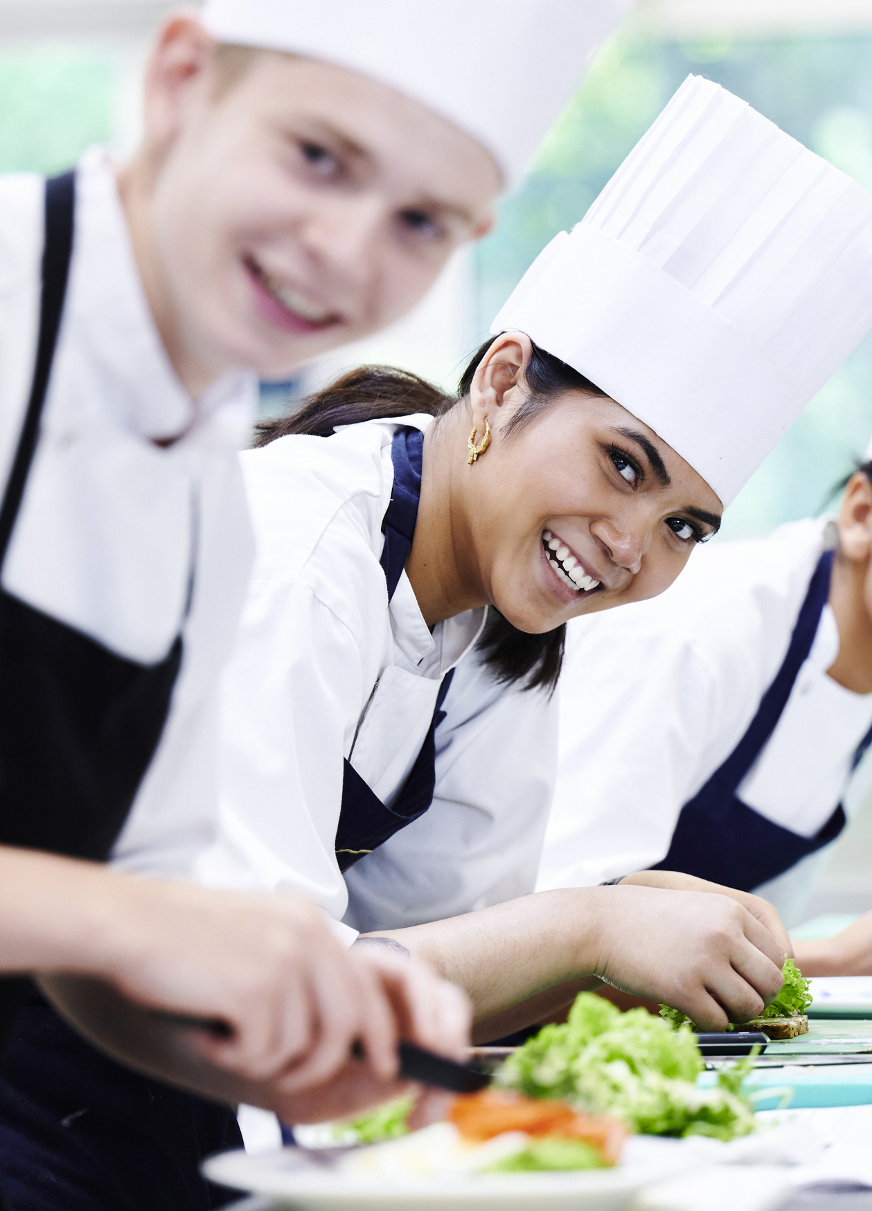 Elever i køkkenet smiler til kameraet