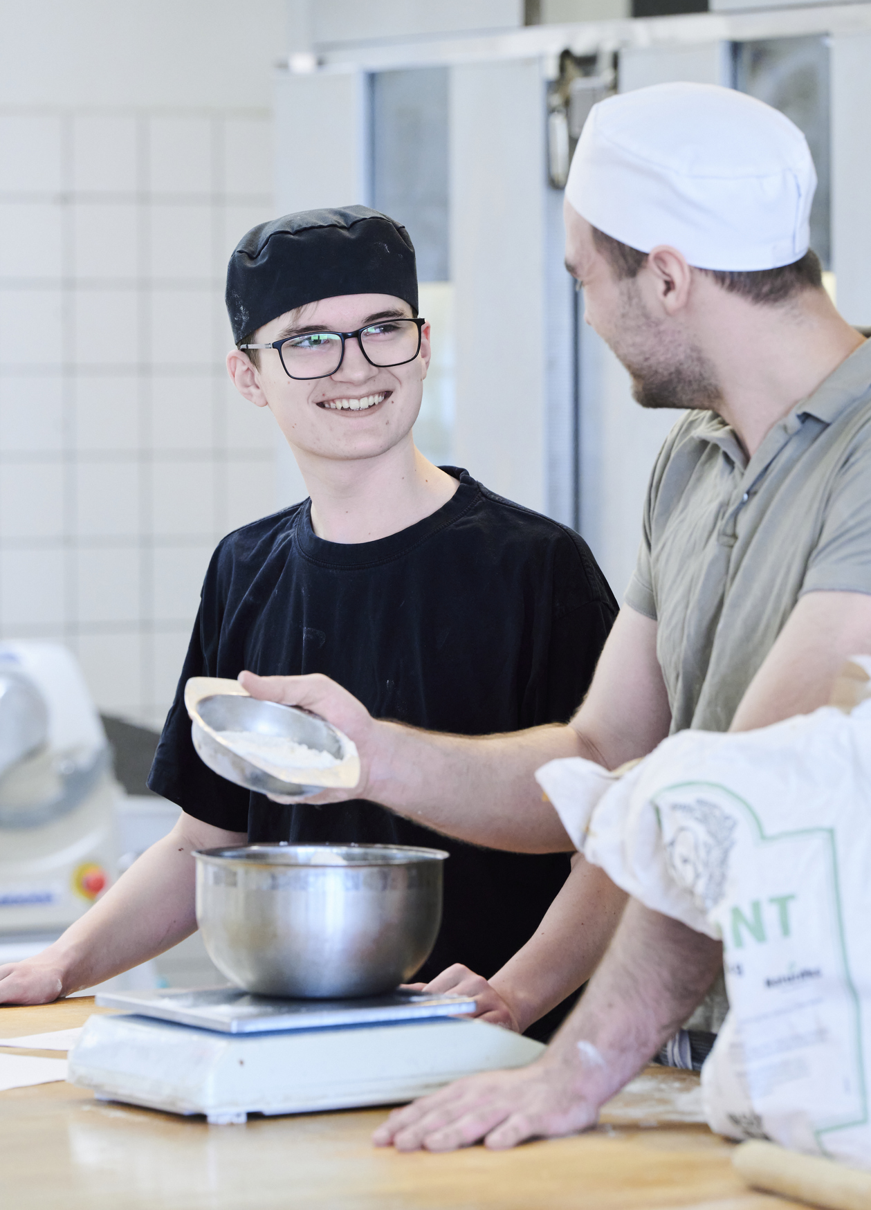 Bagerelever smiler i bageriet