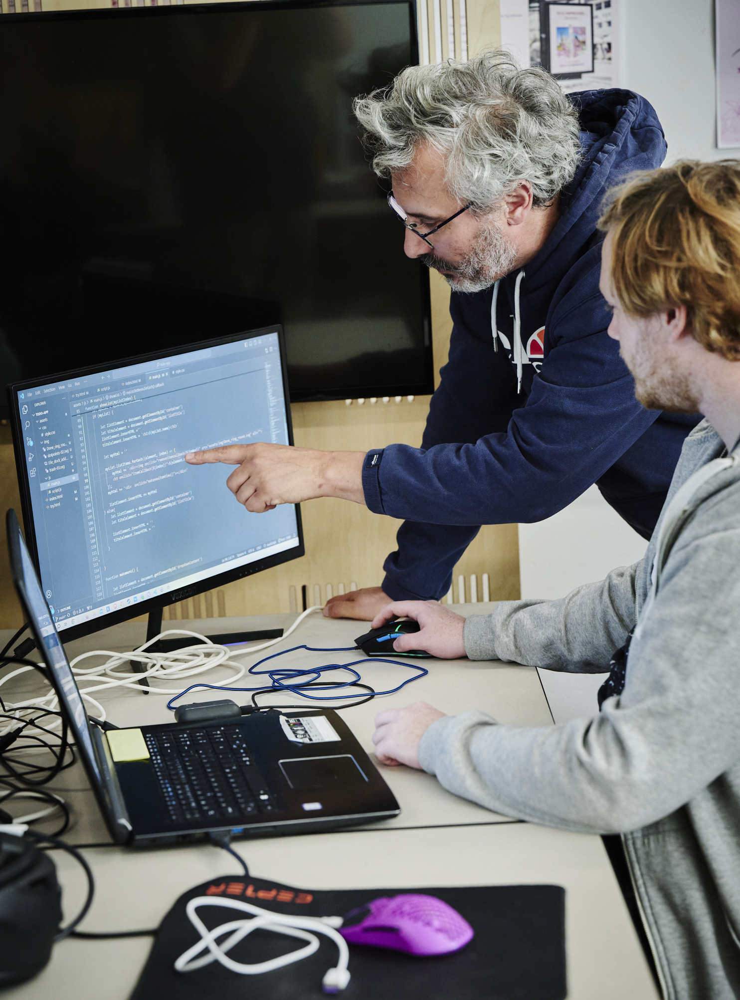 Webudvikler, underviser og elev kigger på skærm