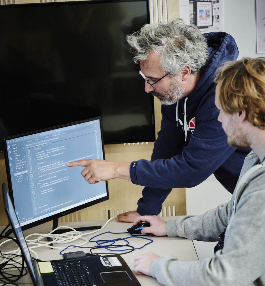 Webudvikler, underviser og elev kigger på skærm