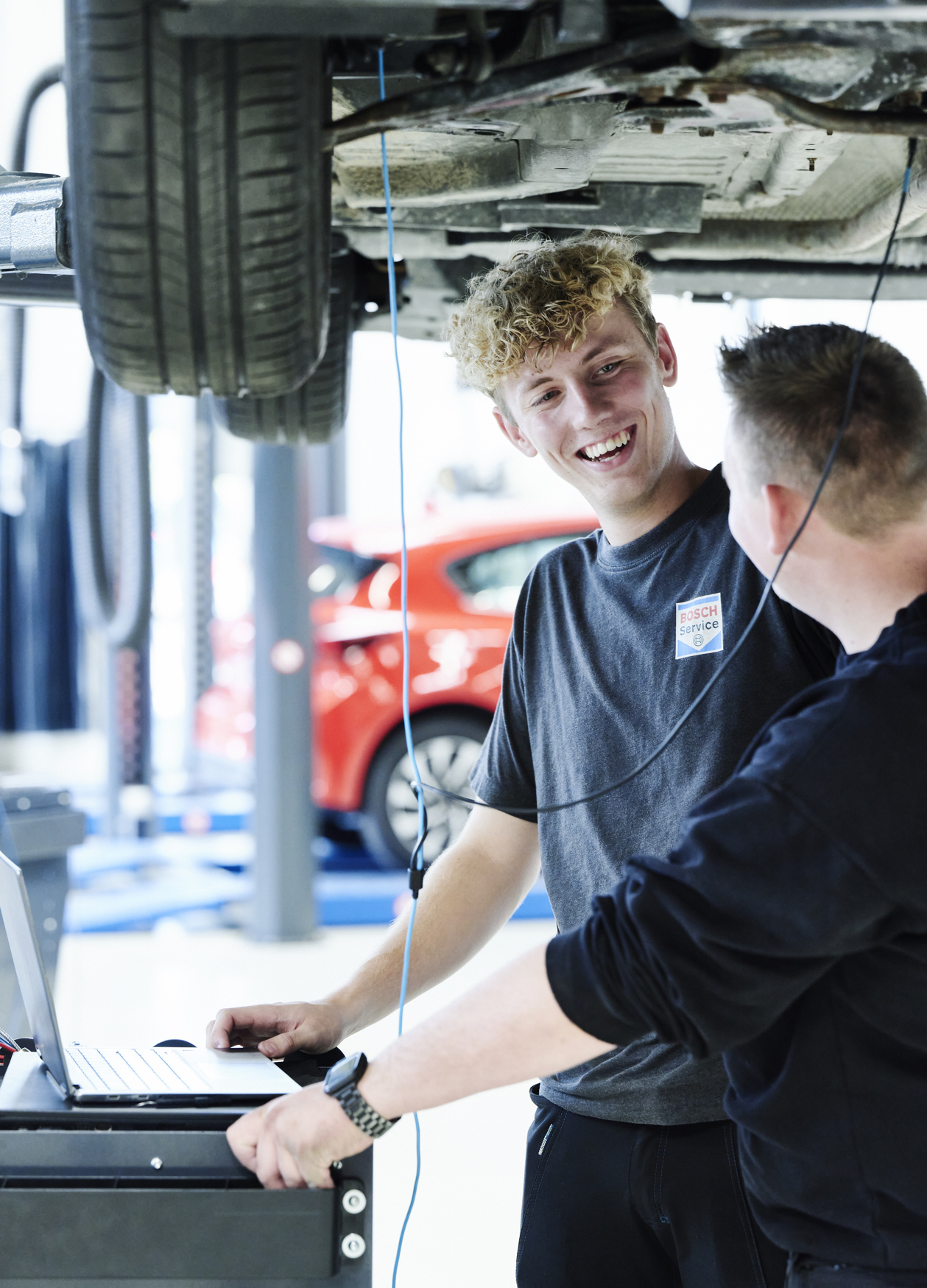 Personvognsmekaniker-elever arbejder under bil