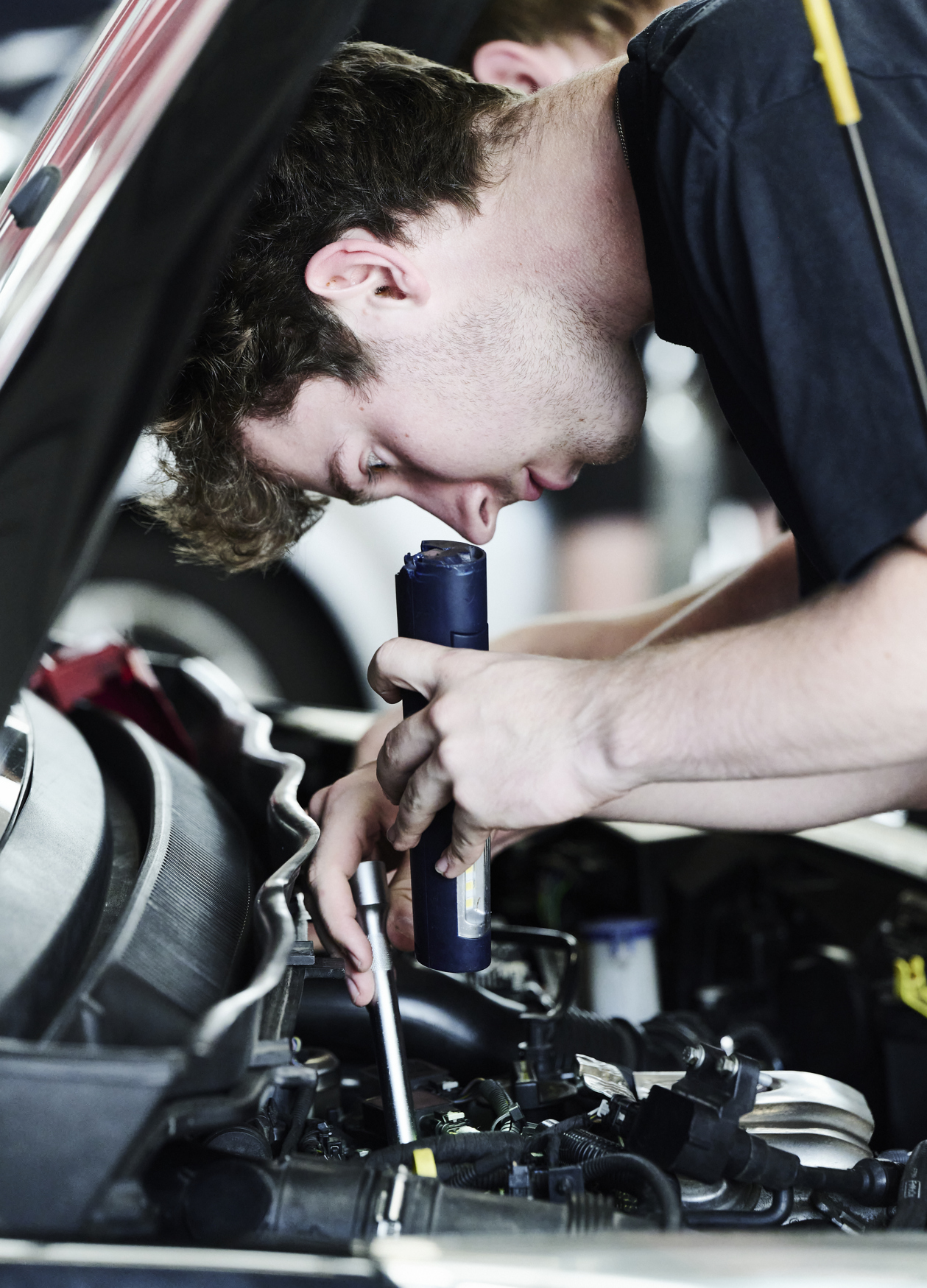 Personvognsmekaniker-elev lyser i motor