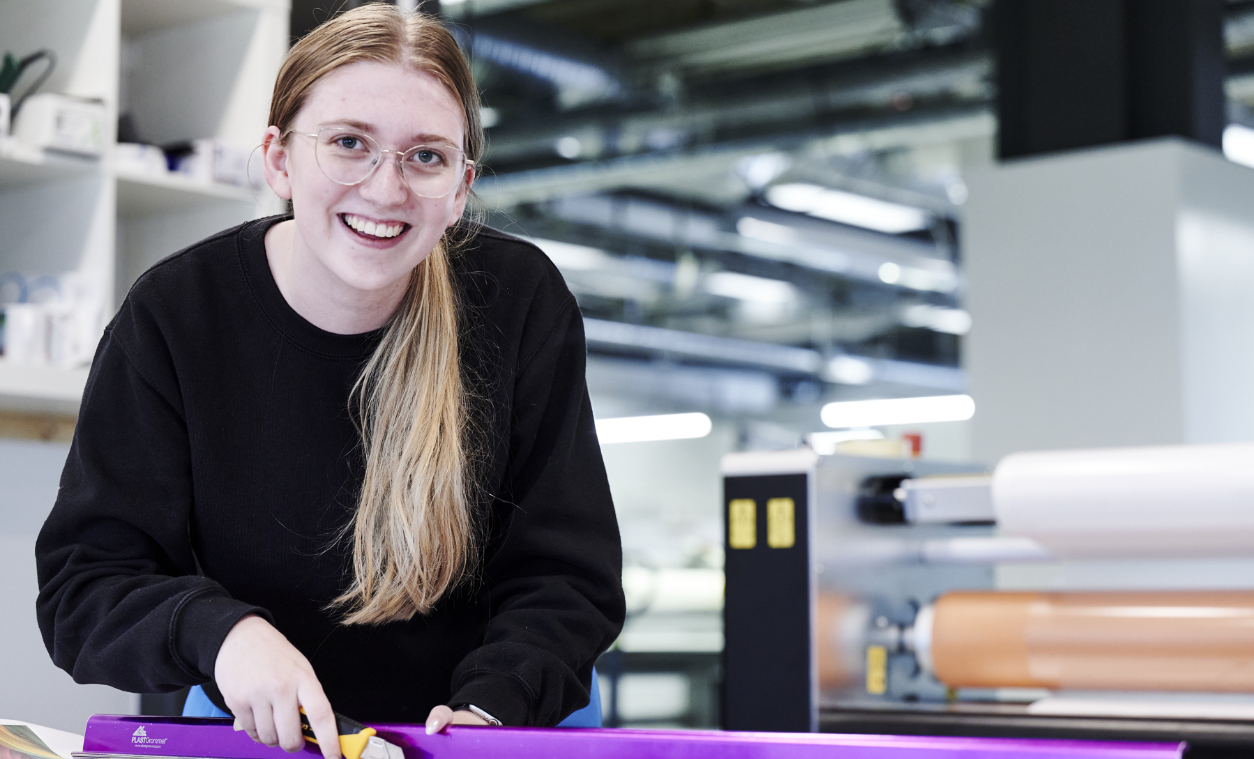 Grafisk tekniker-elev skærer ved skærebord