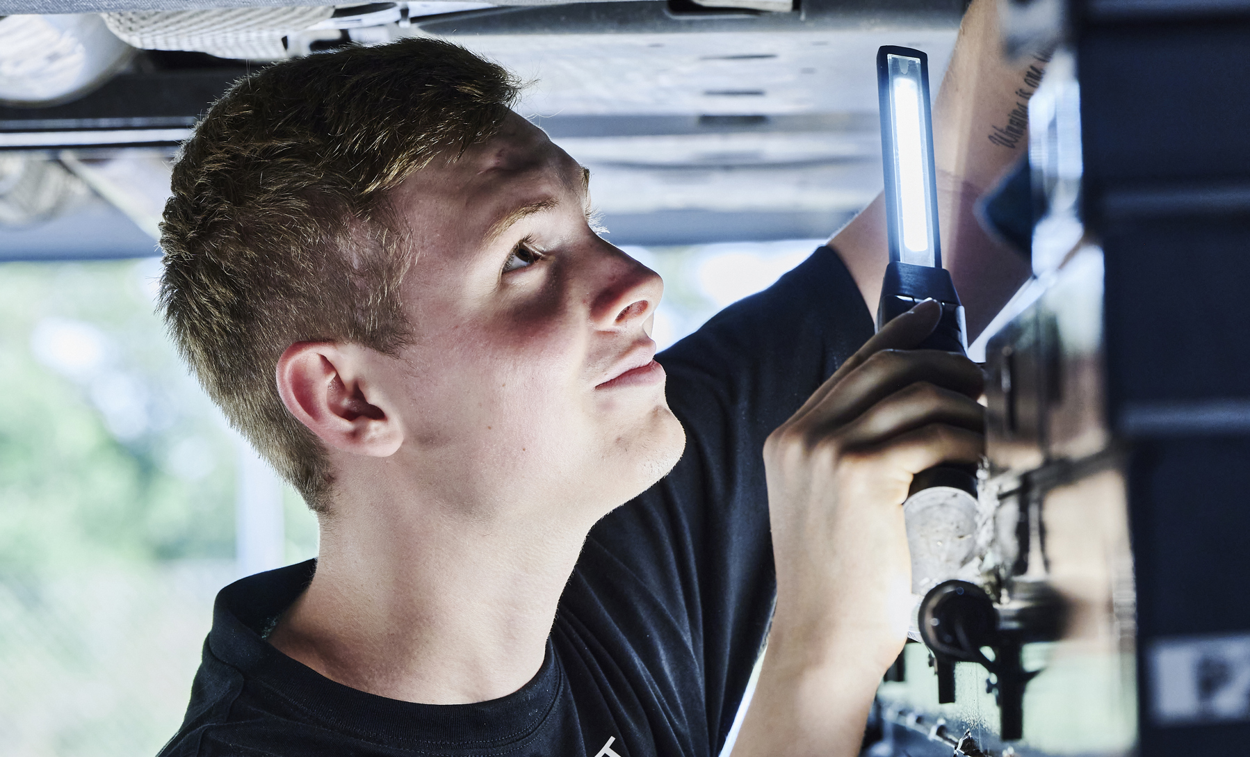 Personvognsmekaniker-elev under bil