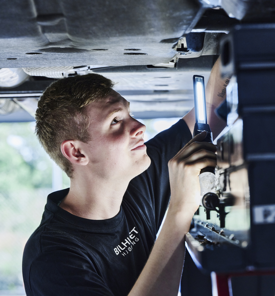 Personvognsmekaniker-elev under bil