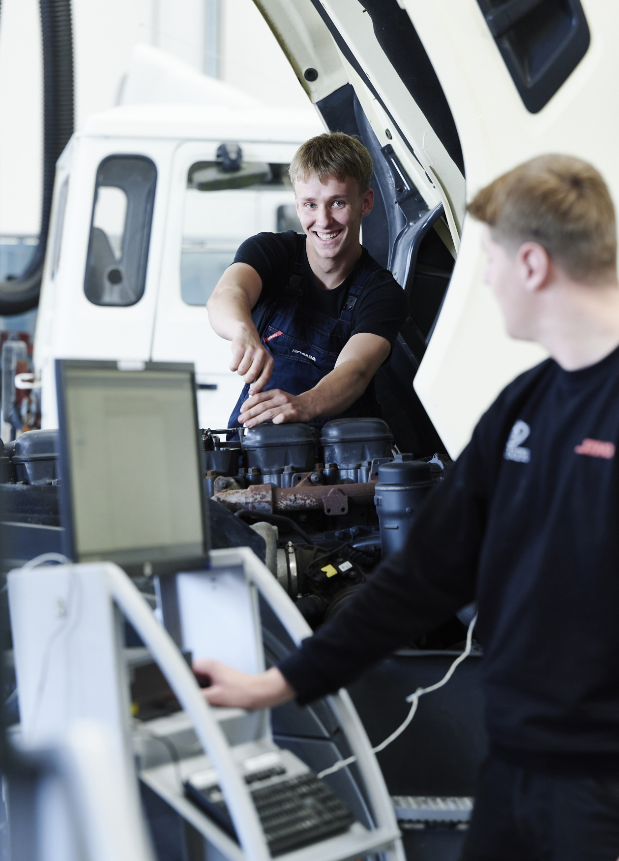 Lastvognsmekaniker-elever skruer på motor