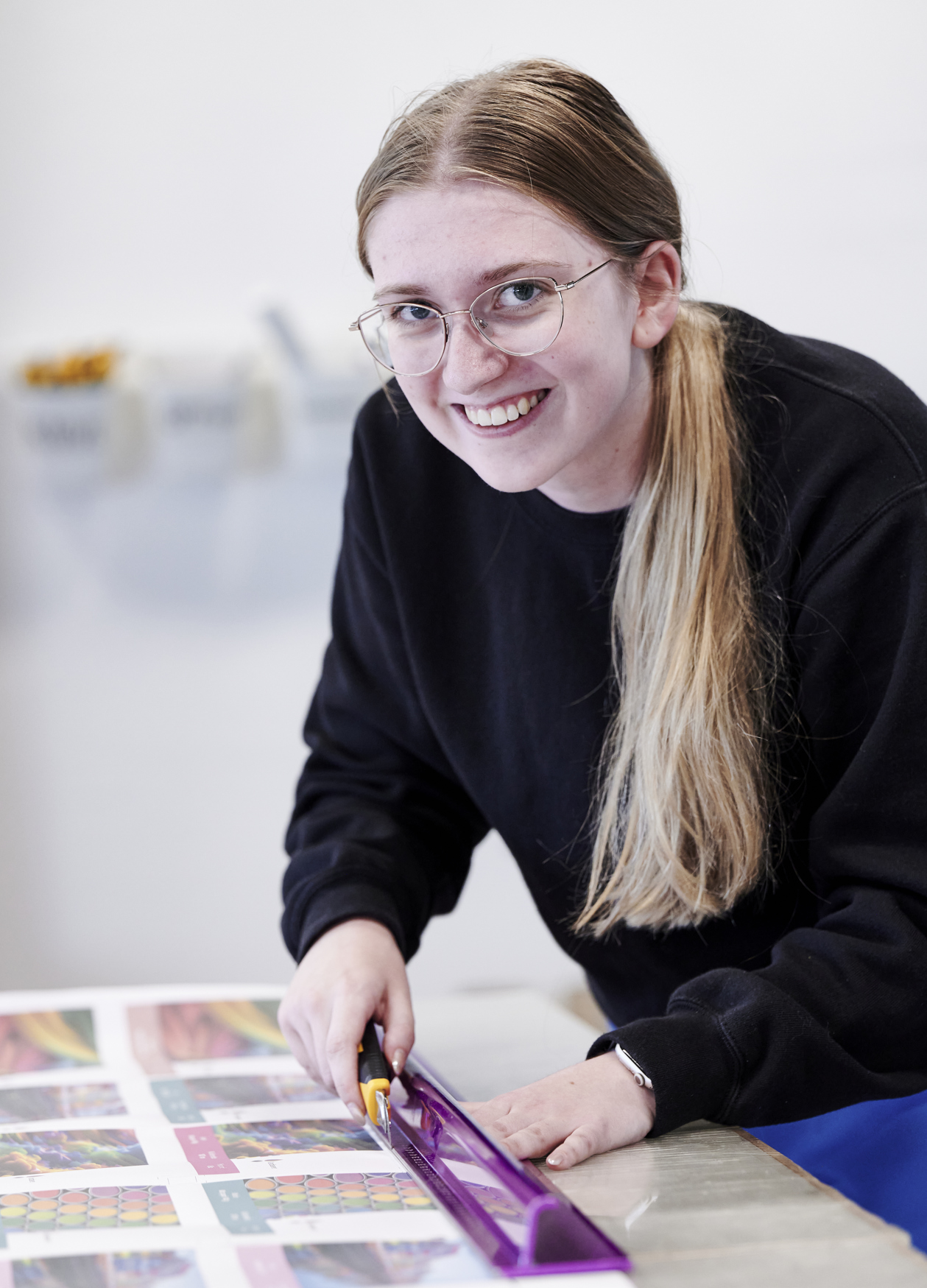 Grafisk tekniker-elev skærer ved skærebord