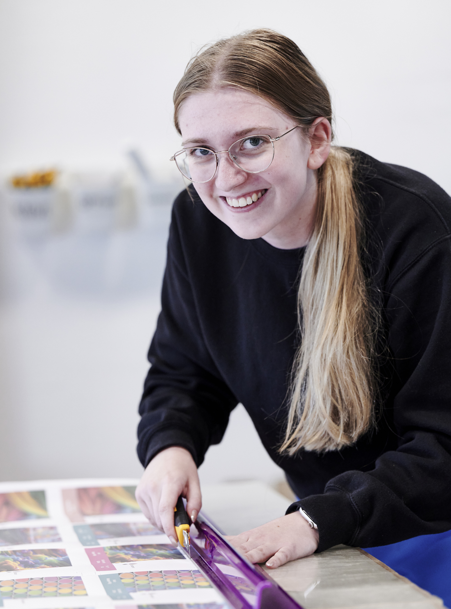 Grafisk tekniker-elev skærer ved skærebord